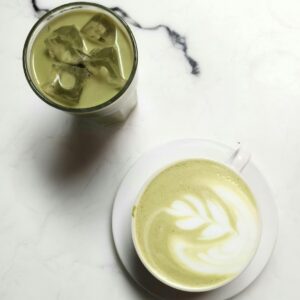 Elegant matcha latte with latte art and iced green tea on a marble table, perfect for tea enthusiasts.