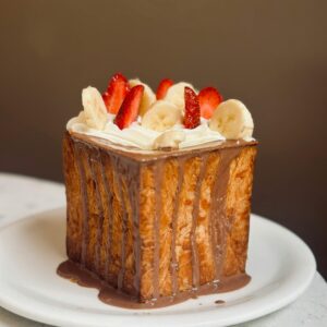 Close-up of a decadent Shibuya honey toast topped with banana, strawberry, and chocolate sauce.